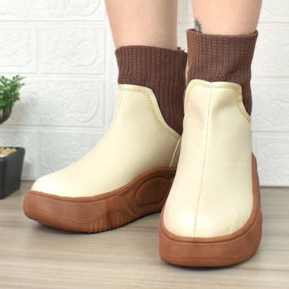 Modelo femenino mostrando Botines Suelaviva Aura en beige desde la rodilla hacia abajo, diseño elegante y cómodo, ideales para cualquier ocasión, lluvia y frío.