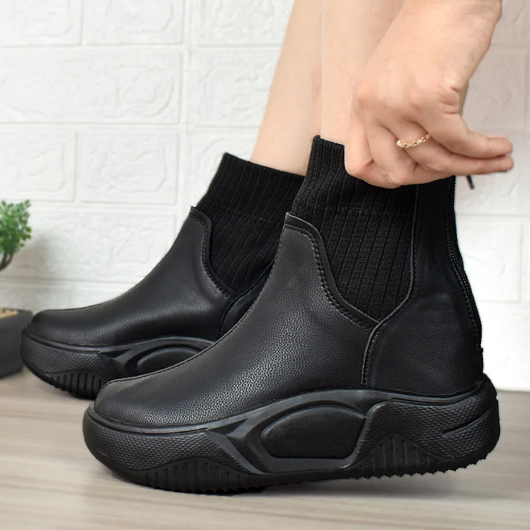 Modelo femenino luciendo Botines Suelaviva Aura en negro desde la rodilla hacia abajo, diseño moderno y único, perfectos para outfits casuales, para el frío y la lluvia.