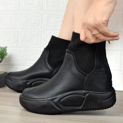 Modelo femenino luciendo Botines Suelaviva Aura en negro desde la rodilla hacia abajo, diseño moderno y único, perfectos para outfits casuales, para el frío y la lluvia.