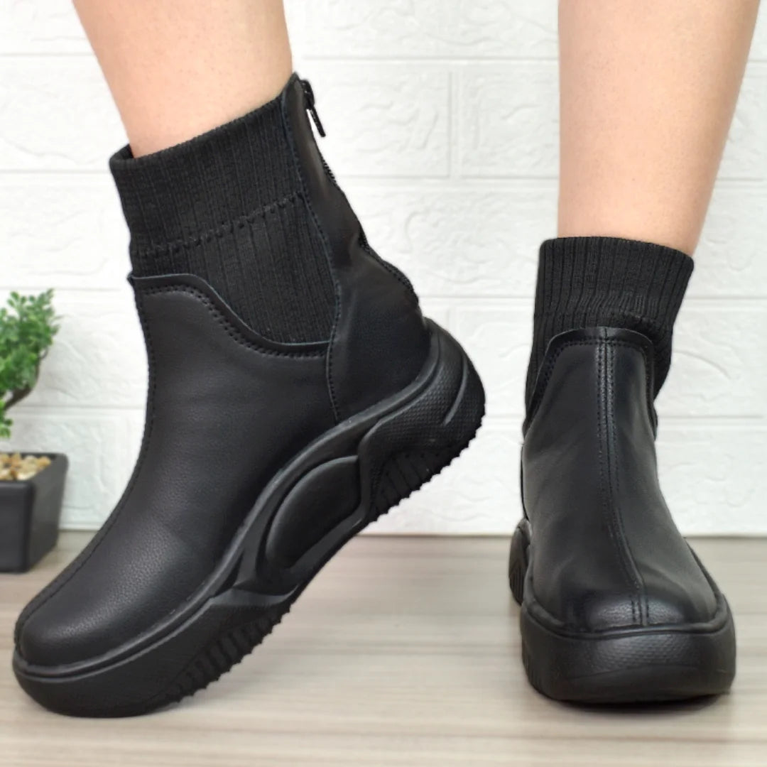 Modelo femenino luciendo Botines Suelaviva Aura en negro desde la rodilla hacia abajo, diseño moderno y único, perfectos para outfits casuales, faldas y estilos modernos.
