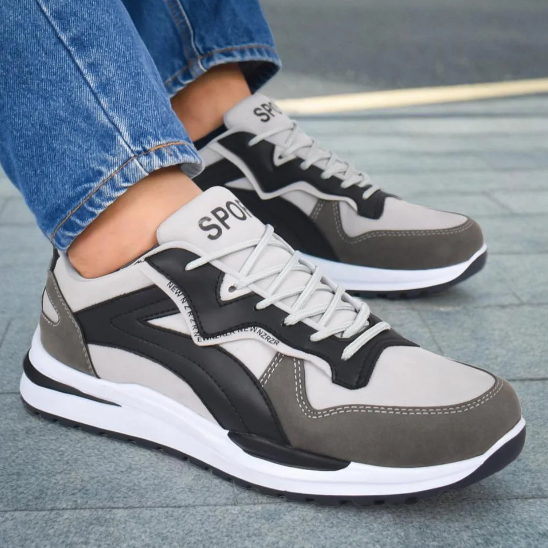 Modelo masculino exhibiendo Tenis Suelaviva Rivo en negro desde la rodilla hacia abajo, diseño moderno con colores en bloques, ideal para un estilo dinámico y un estilo elegante y sobrio.