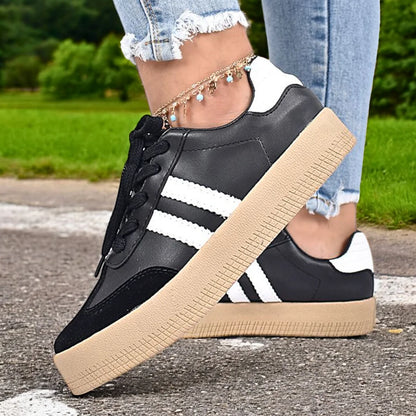 Modelo femenino luciendo Zapatilla Suelaviva Vento en negro desde la rodilla hacia abajo, diseño retro atemporal, perfecta para outfits casuales.