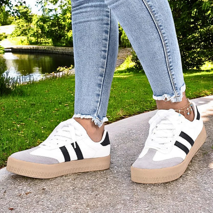 Modelo femenino exhibiendo Zapatilla Suelaviva Vento en blanco desde la rodilla hacia abajo, diseño moderno con colores en bloques, ideal para un estilo dinámico.