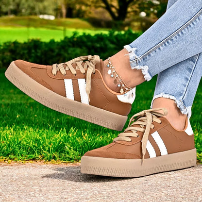 Modelo femenino vistiendo Zapatilla Suelaviva Vento en marrón desde la rodilla hacia abajo, diseño retro y versátil, destacando un estilo activo.